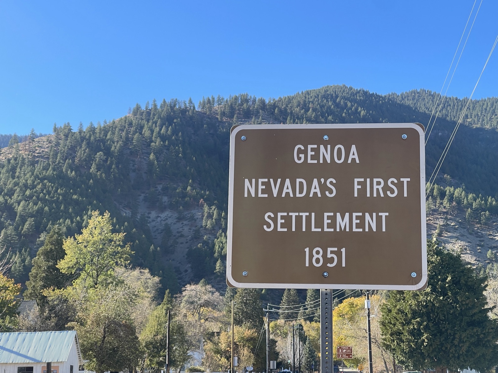 Brown sign reading Genoa, Nevada's First Settlement, 1851, with the Sierra behind it